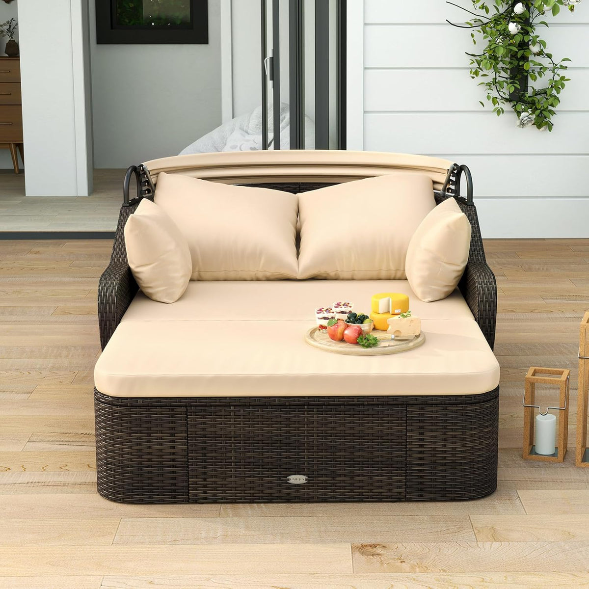 Front view of brown woven rattan daybed with beige cushions and lowered canopy on a patio