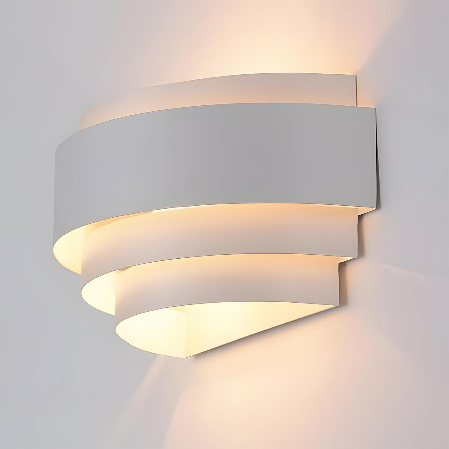 Angled view of white painted metal half-moon wall sconce lit to show upward and downward ambient glow