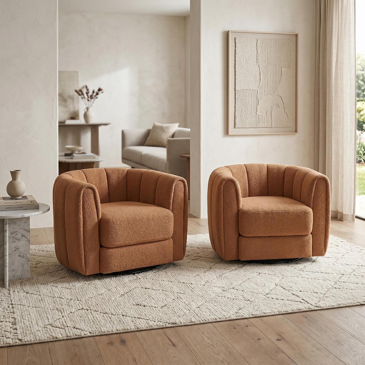 Two rust-colored teddy-fleece swivel barrel chairs on a patterned rug in a neutral living space.