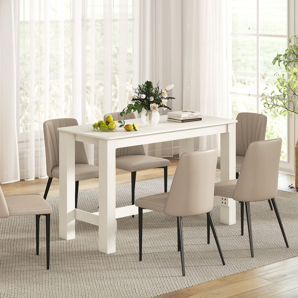 White rectangular dining table surrounded by upholstered chairs in a bright dining room