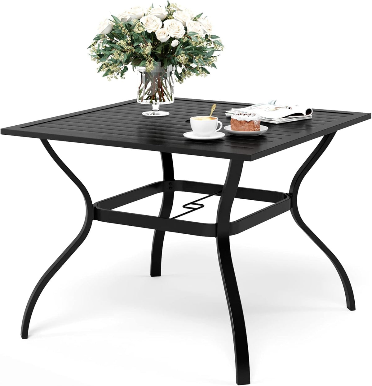 Square black metal outdoor table with slatted top, curved legs and vase, cup, and pastry on top.