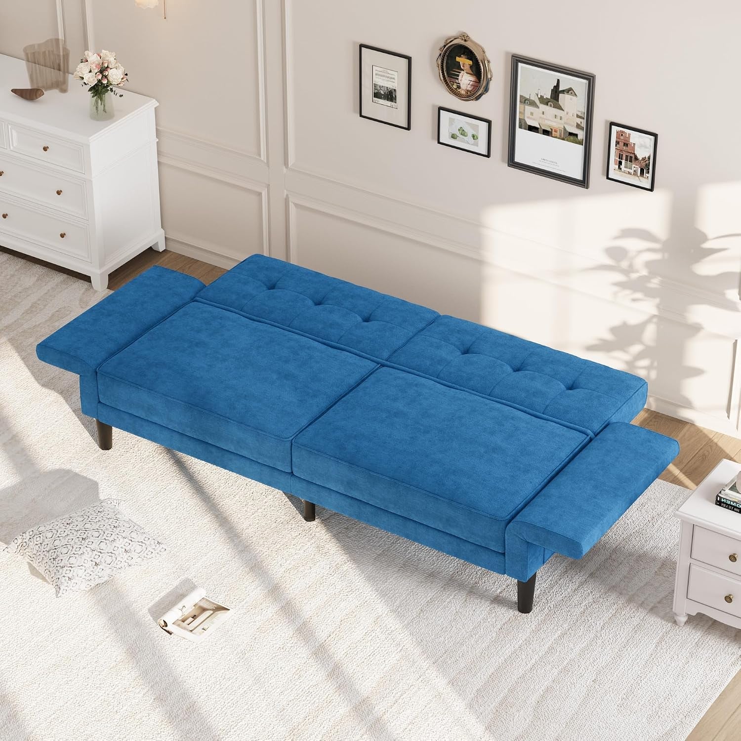 Blue futon laid flat in a bright living room, seen from above with tufted cushions