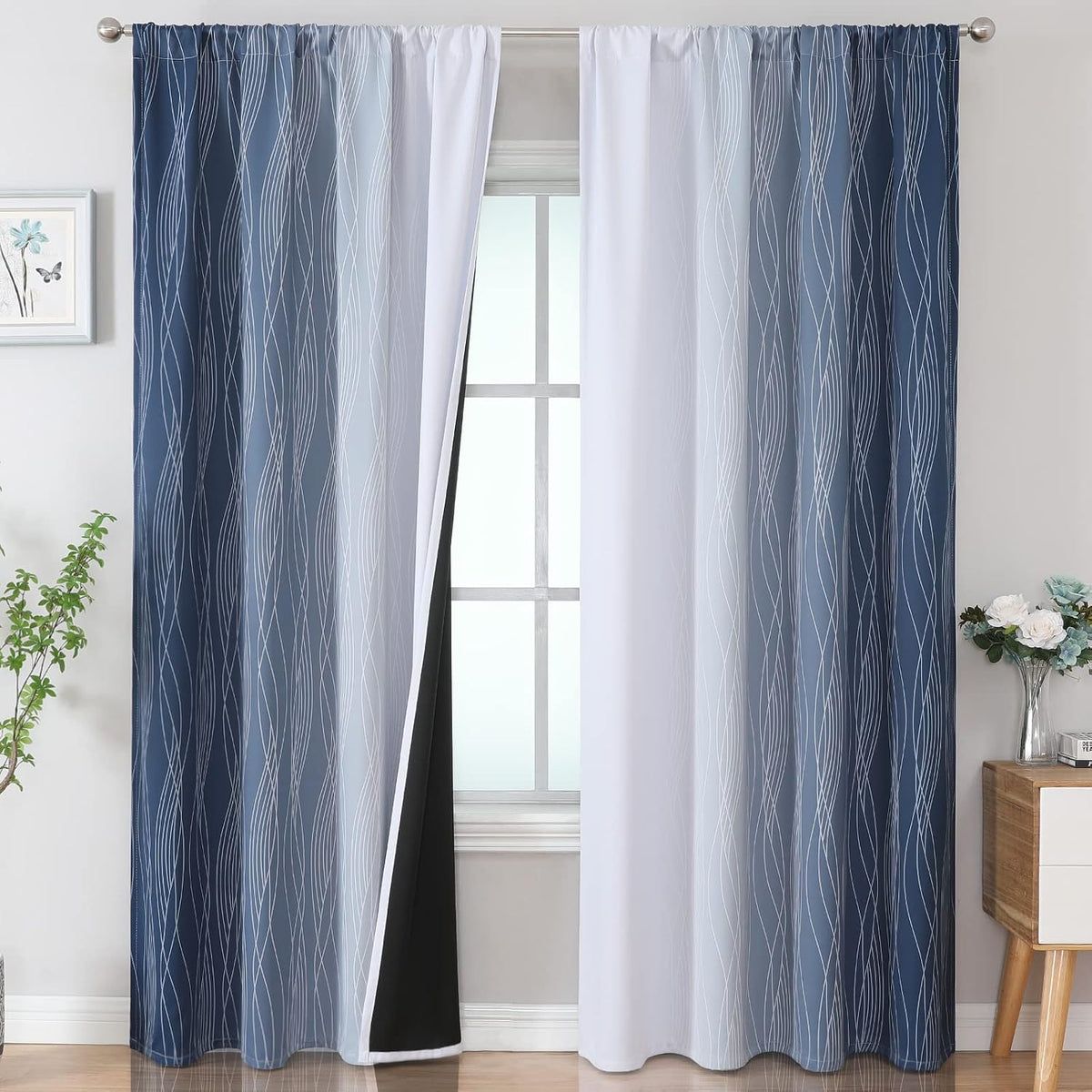 Window with two ombre curtain panels in blue-to-white with wavy line print and black blackout backing visible