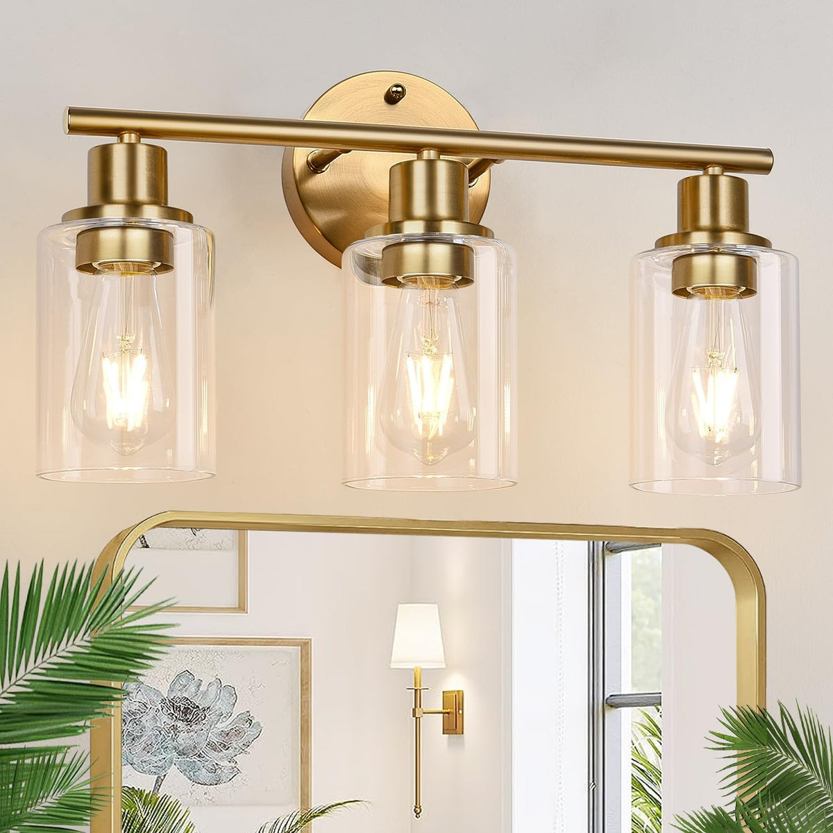 Three-light vanity fixture in a warm gold finish with clear glass shades mounted above a mirror.