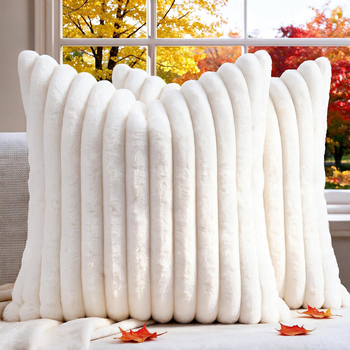 Close-up front view of cream white ribbed faux-fur pillow with autumn trees visible through a window behind