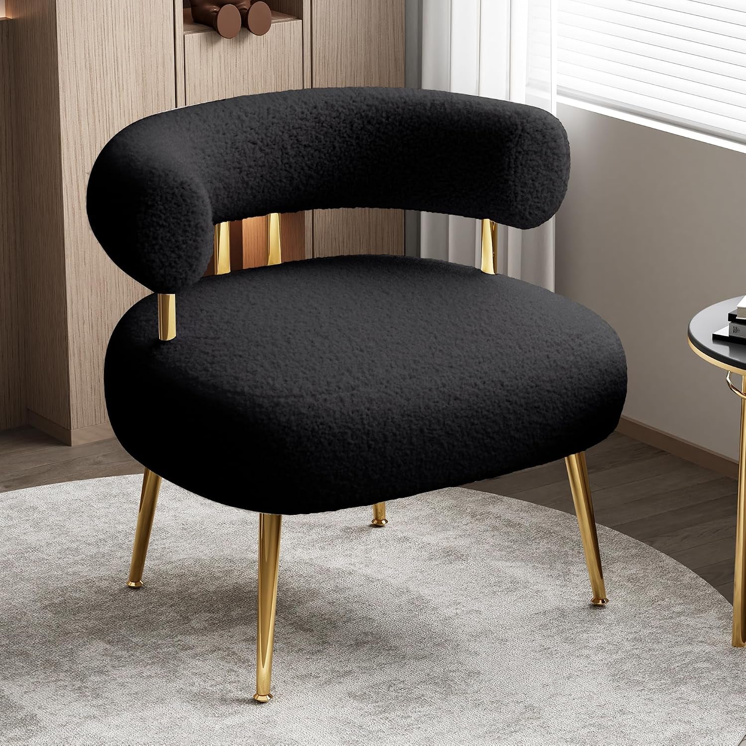 Black rounded barrel accent chair with gold legs set on a circular rug near a side table