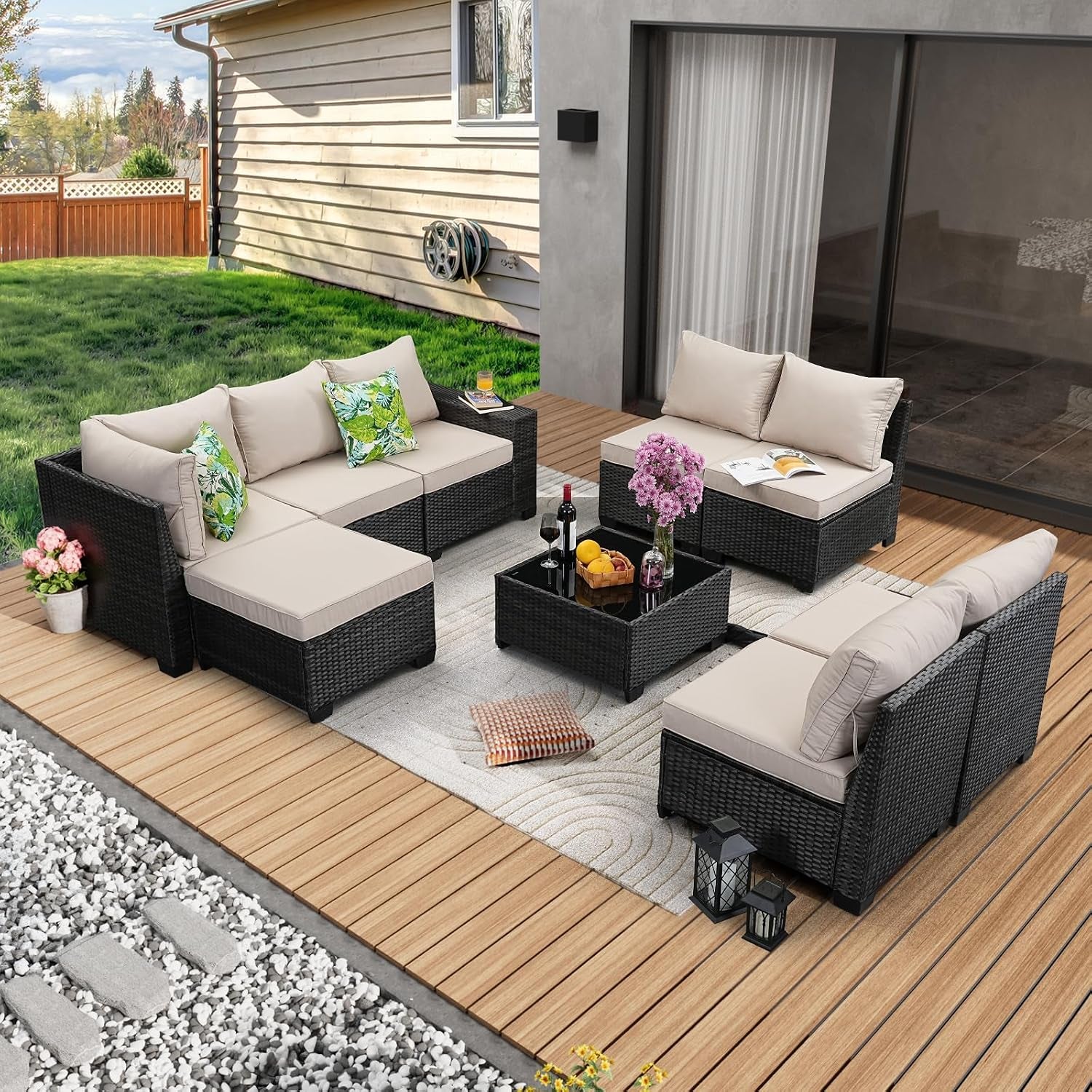 Angled outdoor view of the rattan sectional set with beige cushions on a wood deck and decorative pillows on the sofa.
