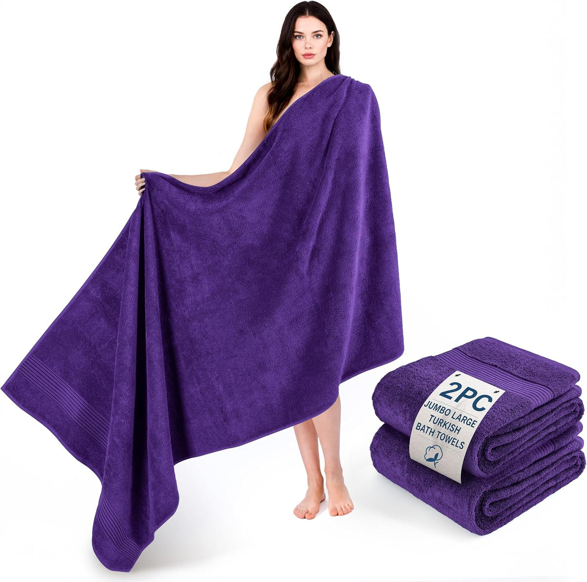 Model holding and draping a large purple bath towel beside a folded purple towel pair on white
