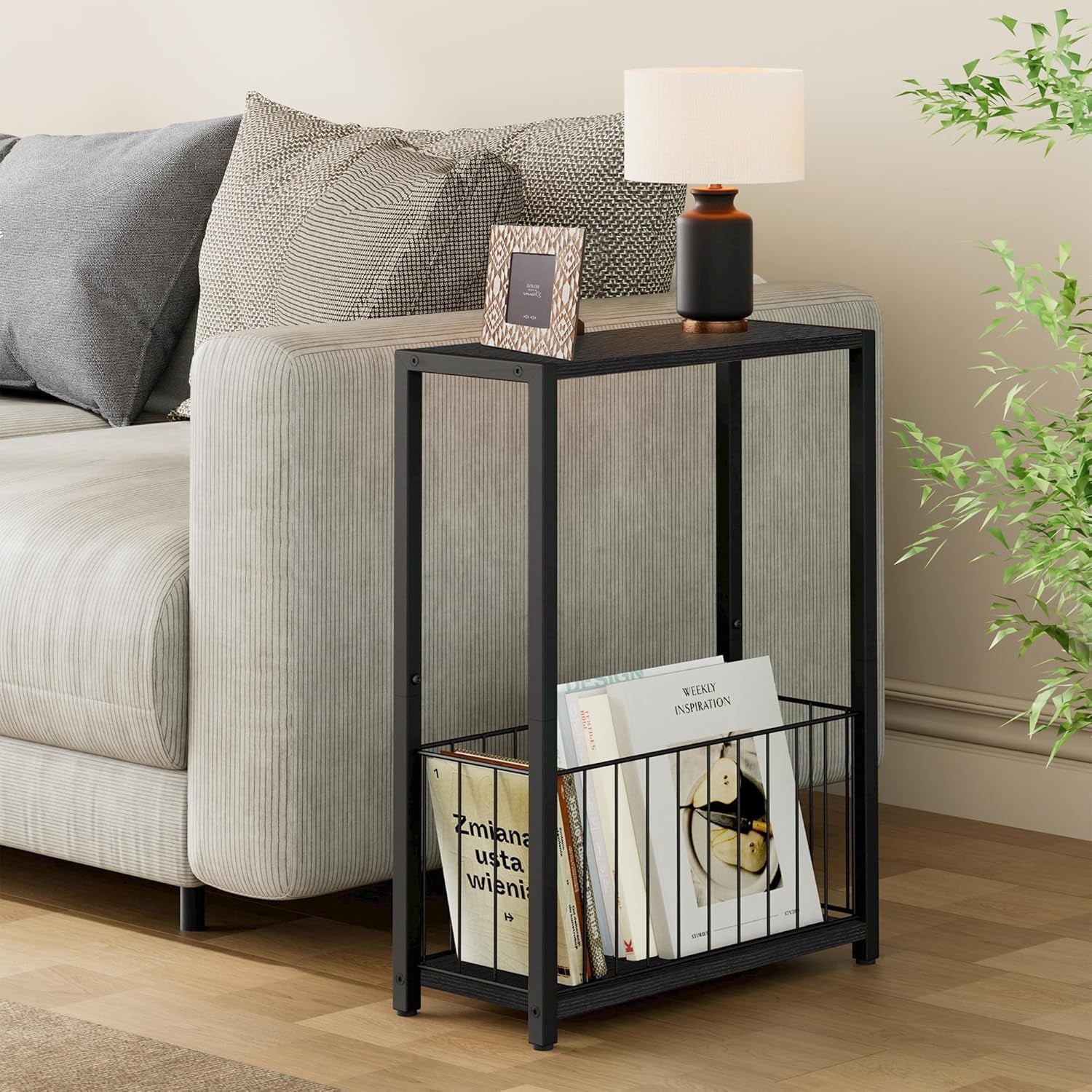 Black narrow side table placed beside a light-colored sofa with lamp and picture on top