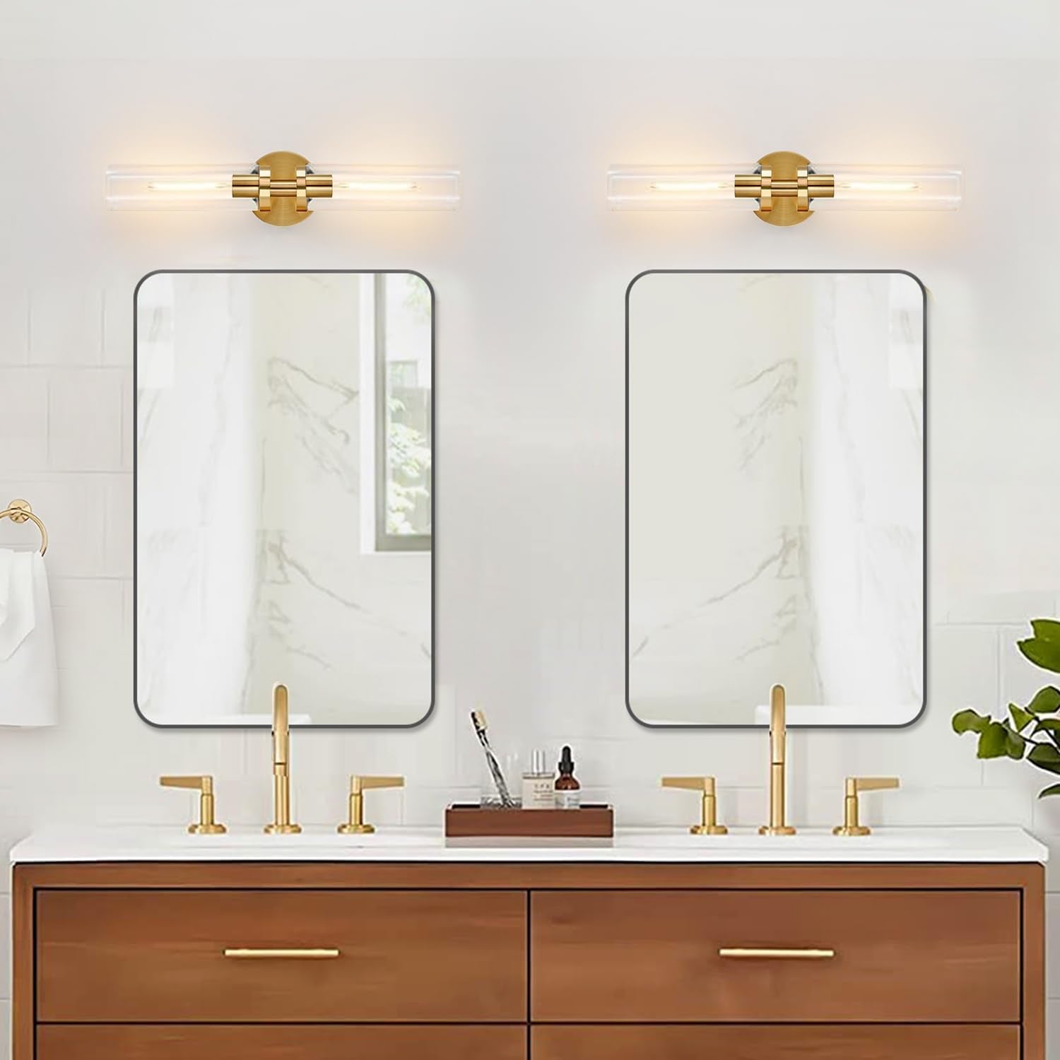 Pair of horizontal gold wall sconces mounted above two slim mirrors and a wooden vanity