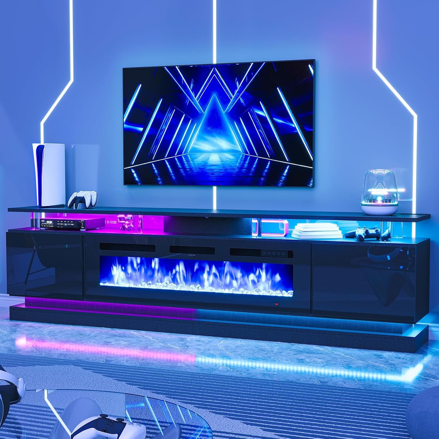 Low-angle front view of a black TV stand with built-in electric fireplace and blue/pink LED lighting under a wall-mounted TV.