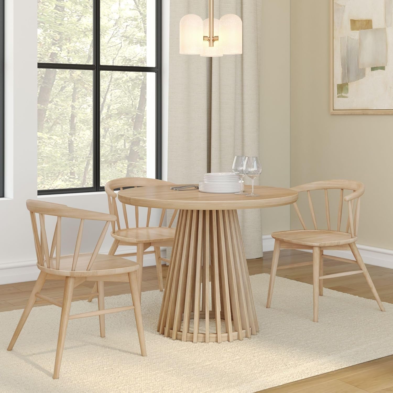 Styled dining scene with the round slatted pedestal table and three matching wooden chairs in a light finish