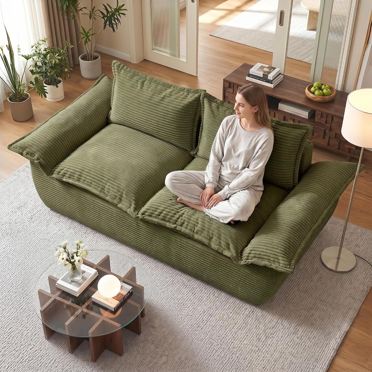 Olive green corduroy sofa viewed from above with a woman seated cross-legged on the cushions