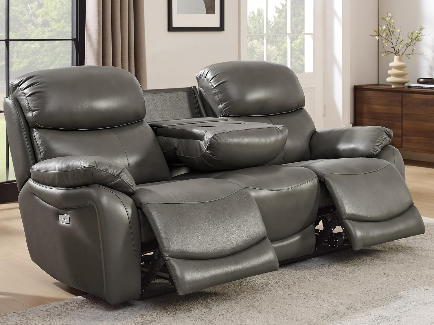 Close front view of a gray leather reclining loveseat with center drop-down table down and both footrests extended
