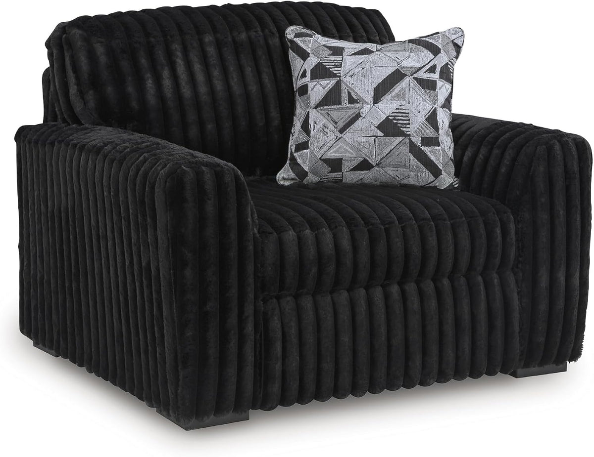 Three-quarter view of a single deep lounge chair in dark corduroy with a geometric patterned accent pillow.