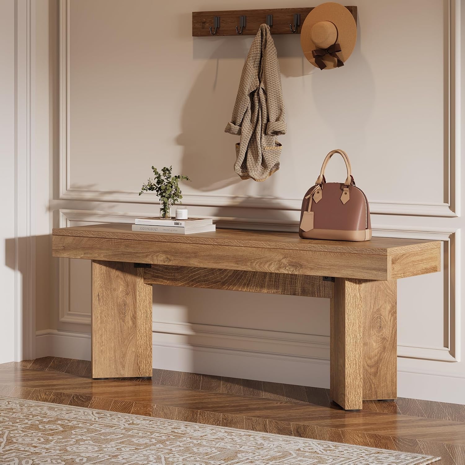 Rustic brown bench in a foyer styling, topped with a small plant, books and a handbag