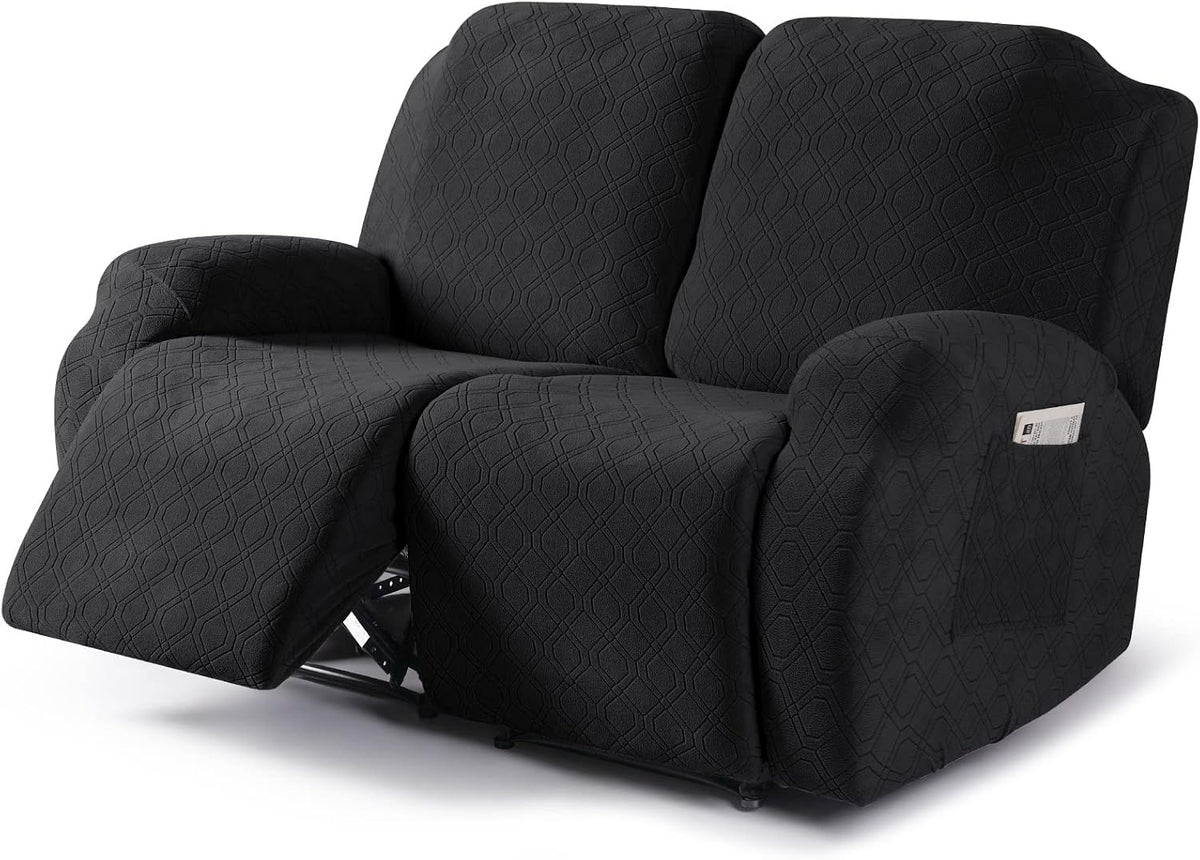Angled front view of a dark gray textured recliner cover on a reclining loveseat, one footrest extended and pocket on the