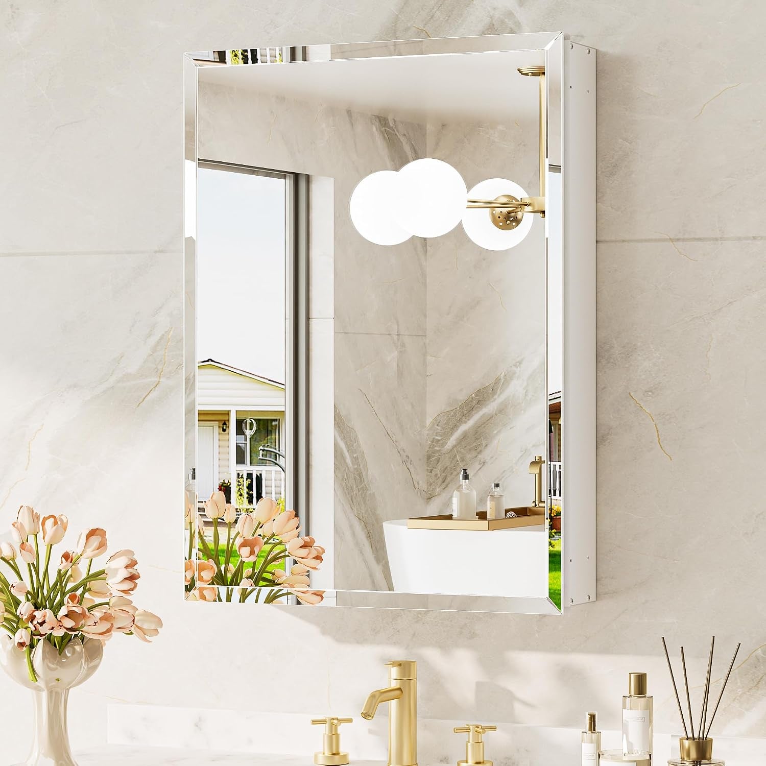 Angled view of the mirrored cabinet reflecting a chandelier and bathroom décor with gold faucet below.