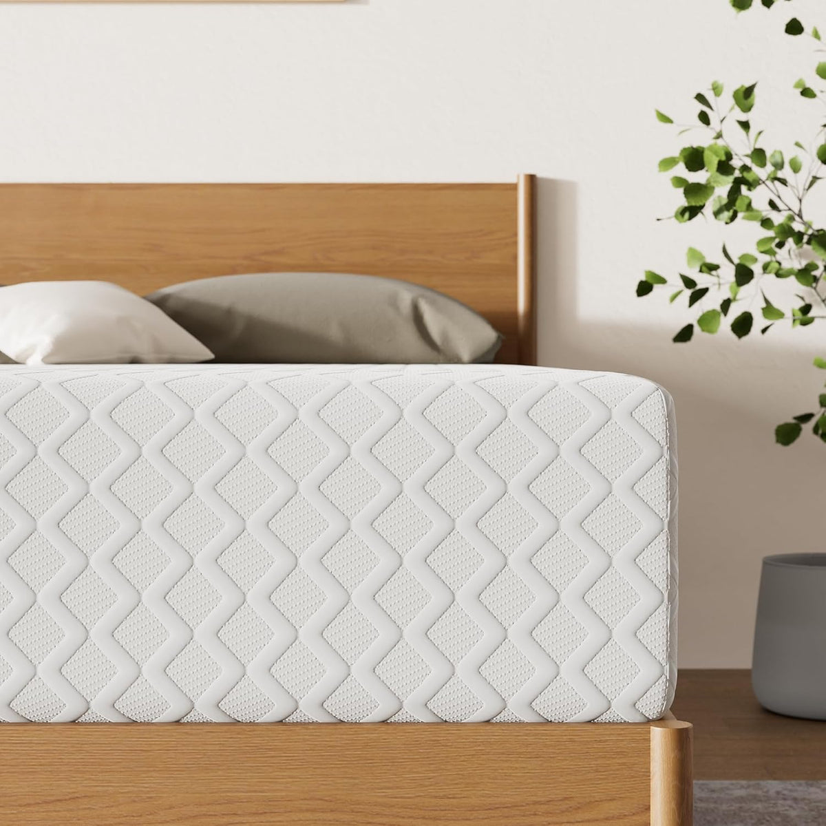 White quilted memory foam mattress side view on a wooden platform bed with headboard and a potted plant