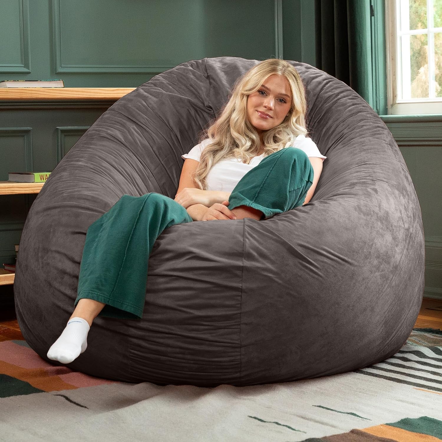 Charcoal-grey bean bag formed into an upright wraparound chair with a woman seated against a green wall