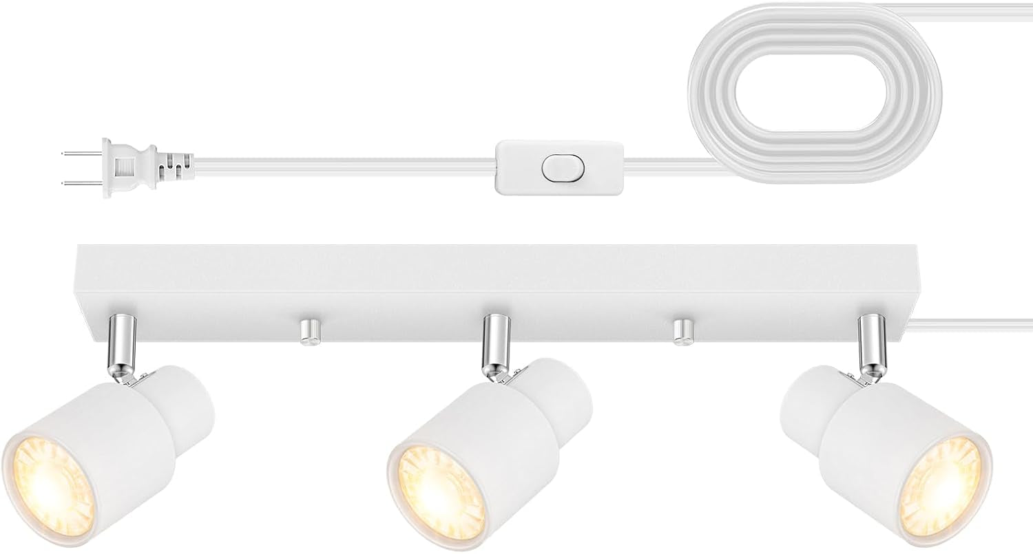 White track bar with three tilted lit spotlights laid flat alongside coiled cord and inline switch