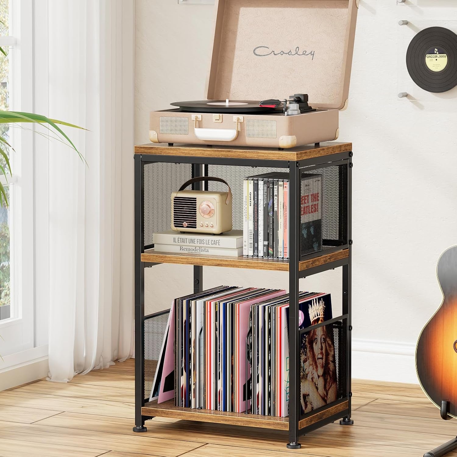 Tall three-shelf table with black metal mesh sides holding a stack of vinyl records and a small retro radio on the middle