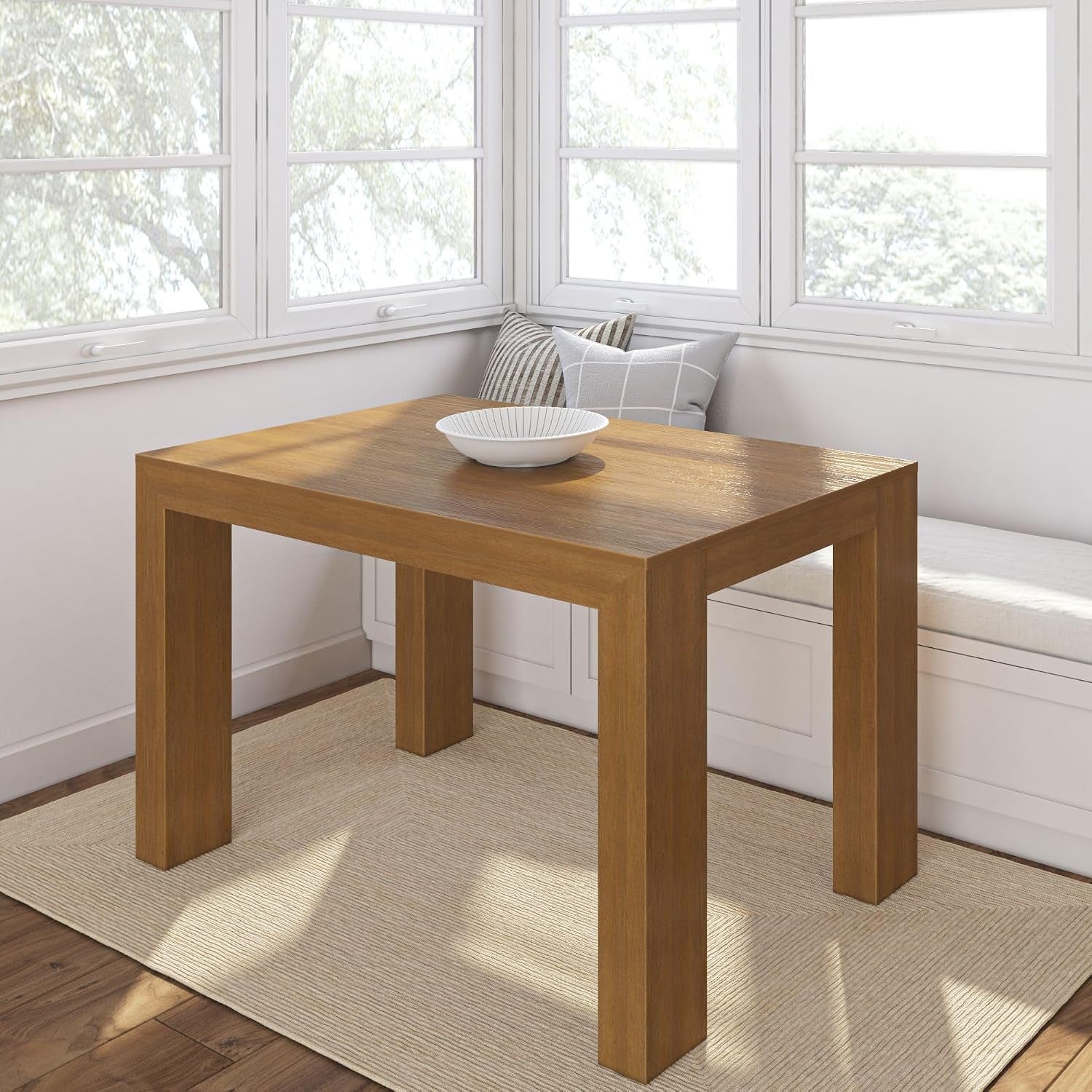 Square solid pine dining table in warm honey brown finish in a bright corner with bowl on top