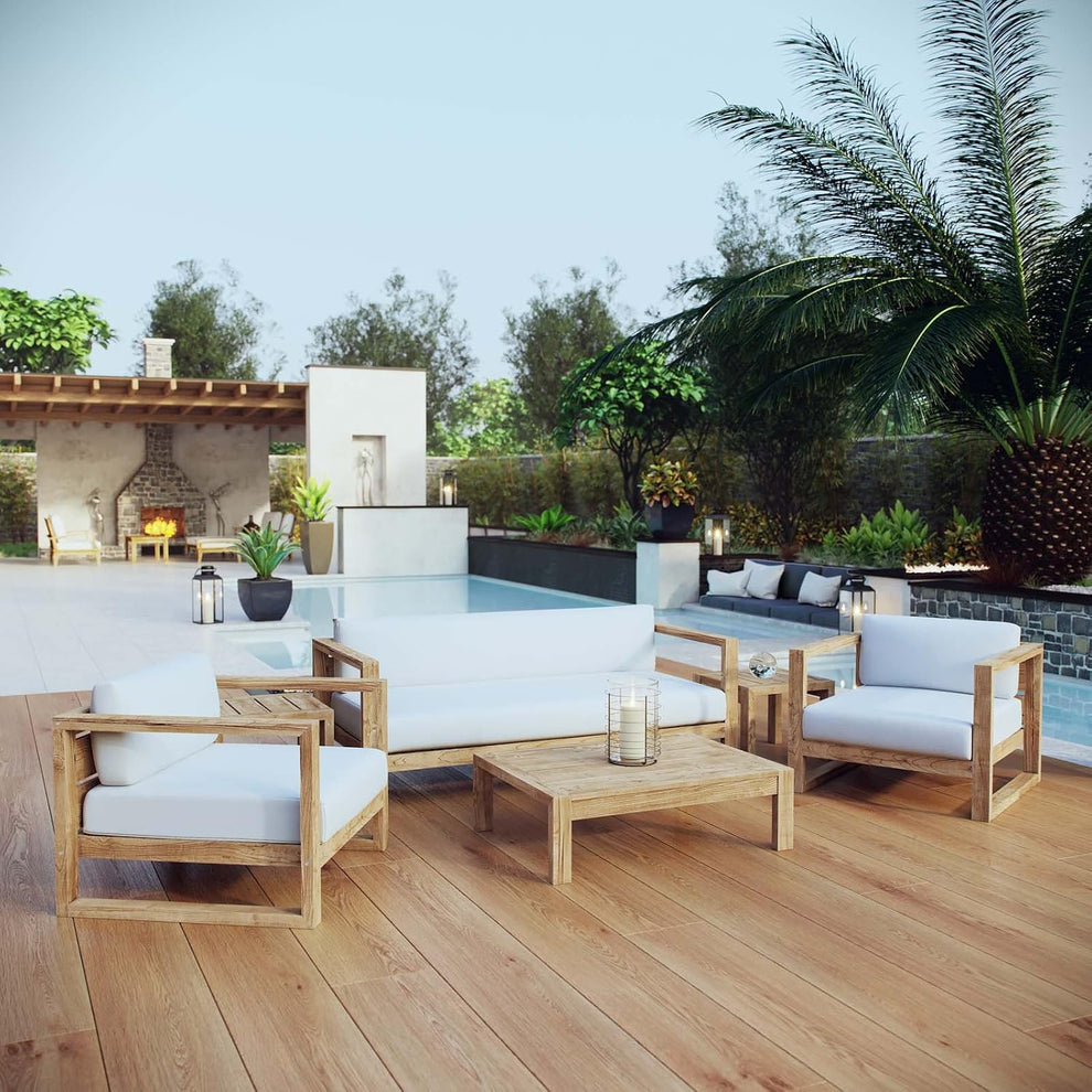 Poolside teak seating group with low table on wide wood deck, palm tree and pergola in background