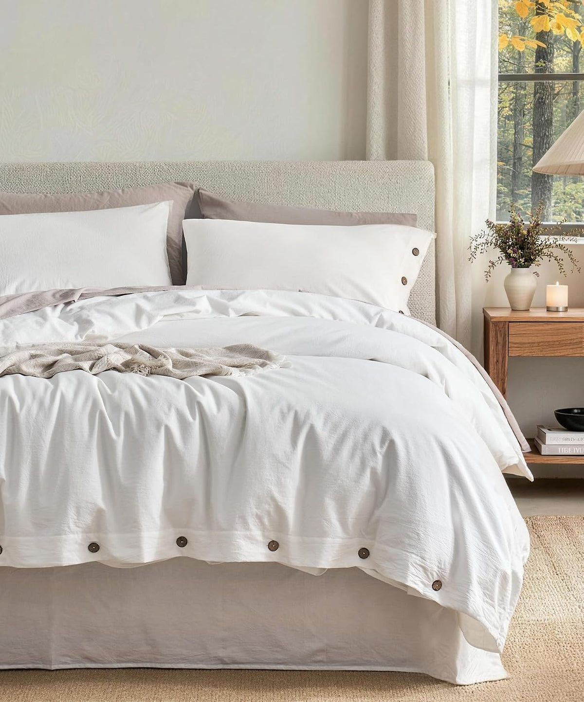 Front view of a bed dressed in a crisp white duvet with button hem and beige pillow shams