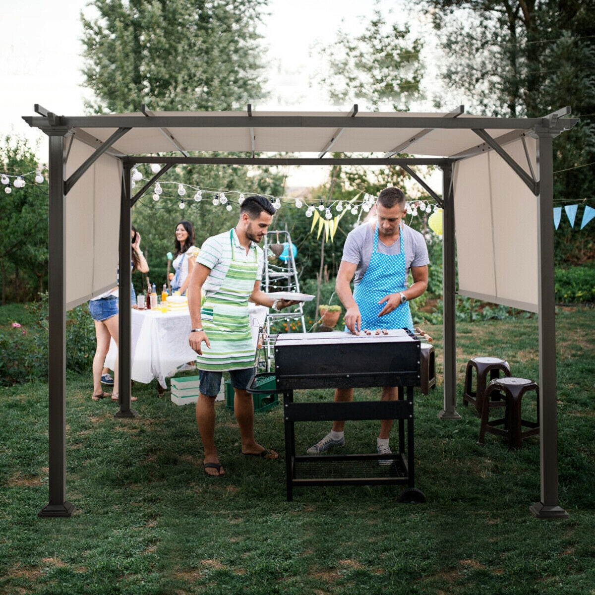 People gather around a barbecue beneath the beige-panel shelter in a garden.
