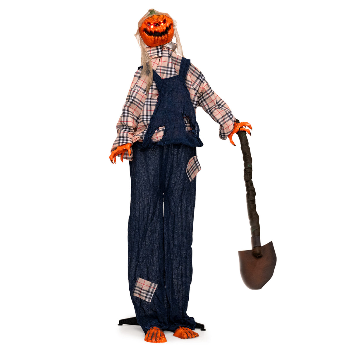 Full-length view of a pumpkin-headed scarecrow in patched overalls, holding a shovel against a white background.