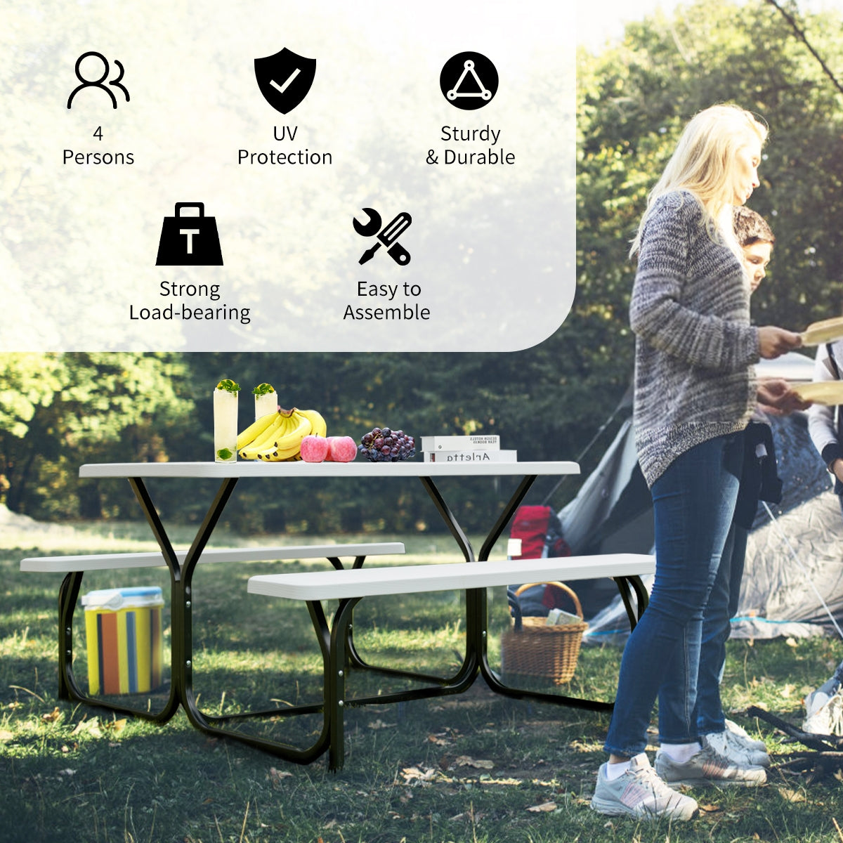 Picnic table and benches set up at a campsite, with fruit on the table and people nearby.