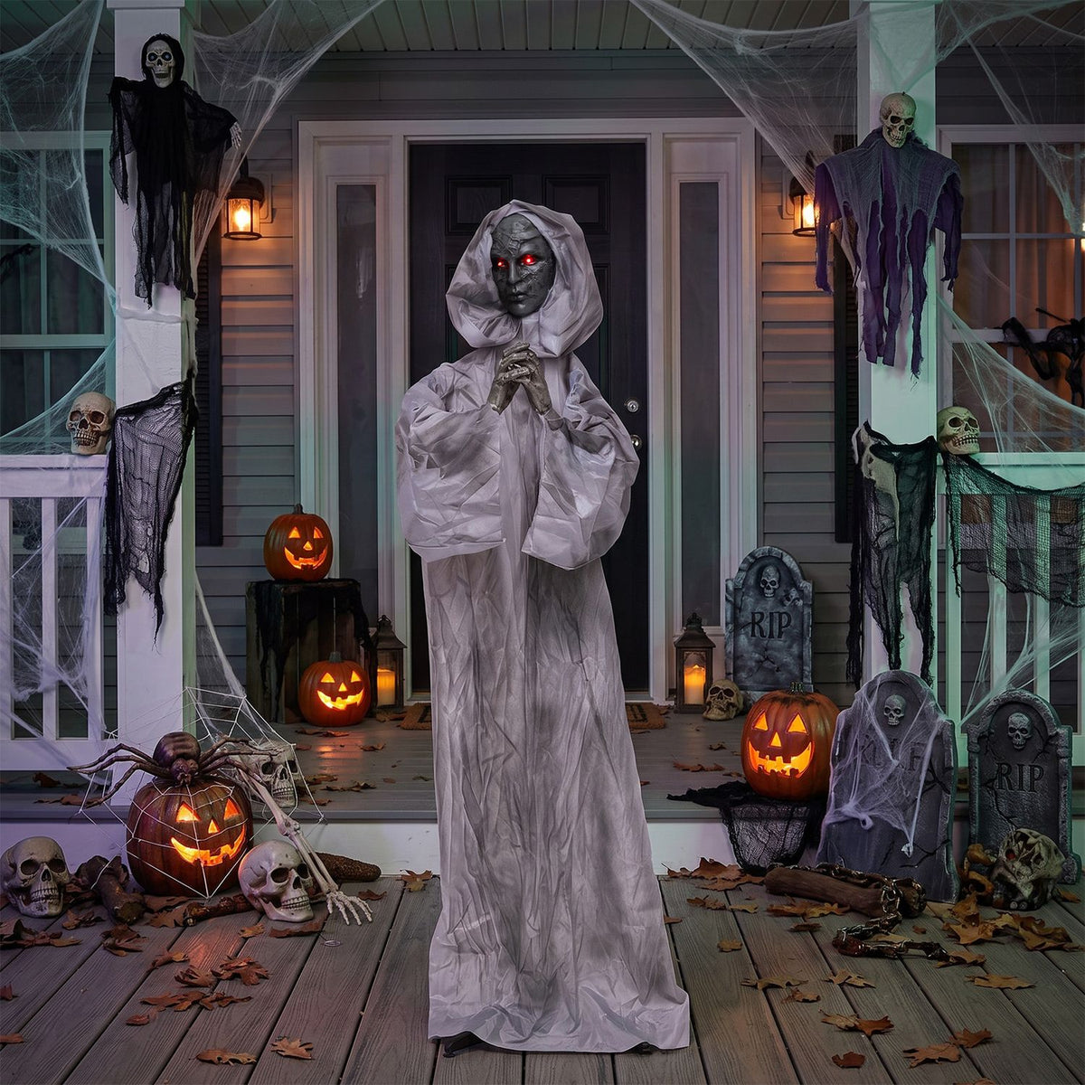 Gray-robed weeping woman animatronic on a porch decorated for Halloween