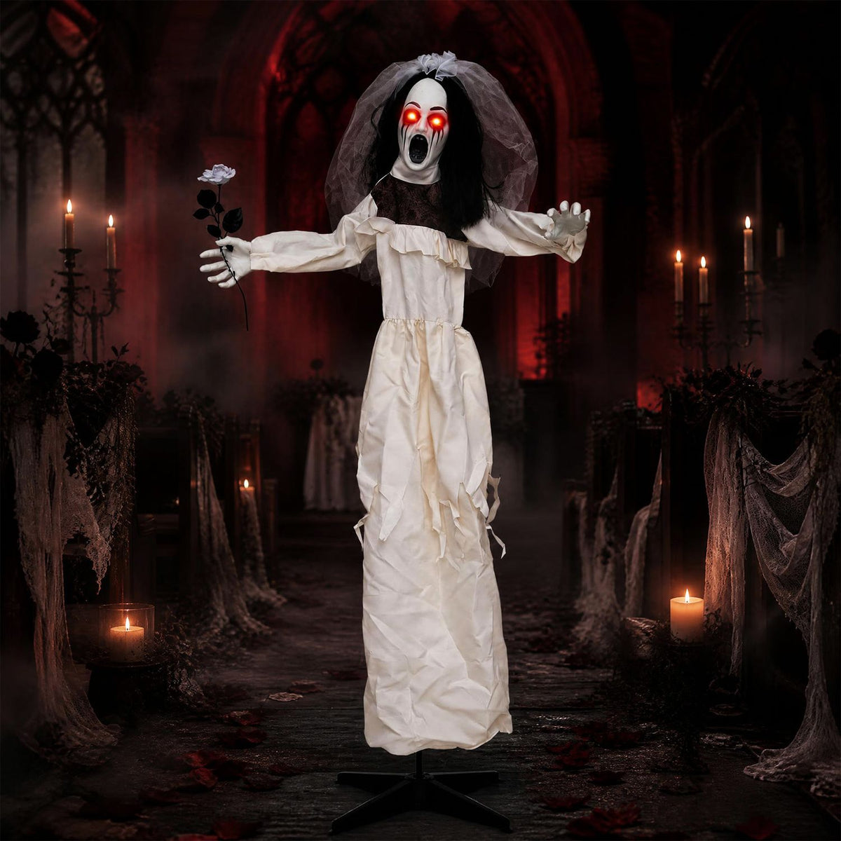 A glowing-eyed bride animatronic in a tattered white dress holds a flower in a candlelit, ruined hall.