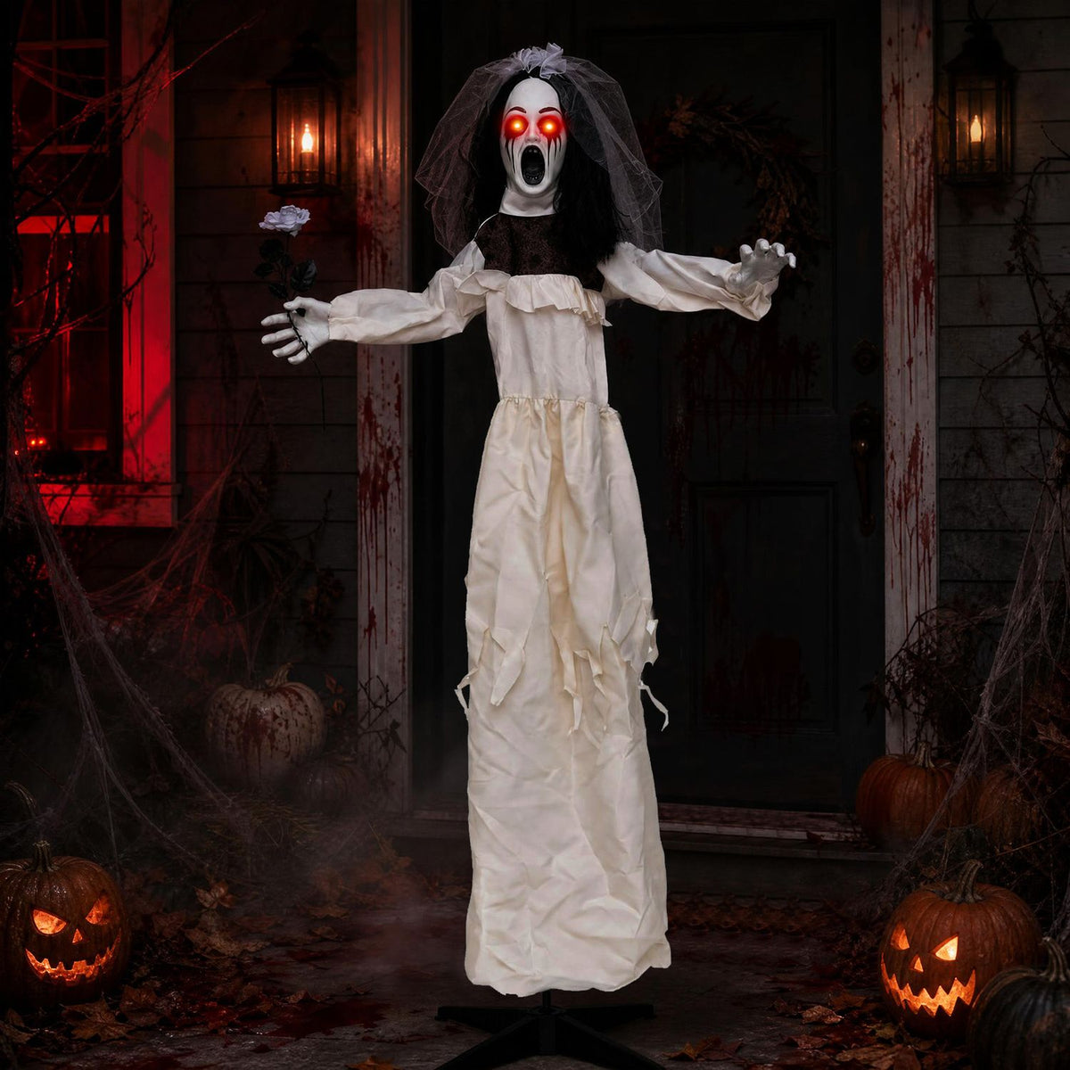 The bride animatronic stands with arms outstretched and a flower, framed by lit jack-o'-lanterns and a dark doorway.