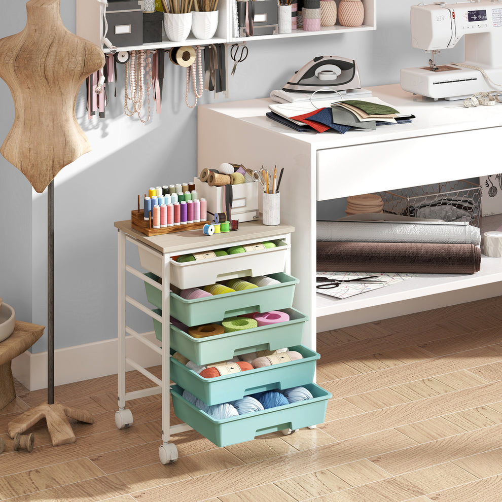 A mint-green drawer cart with a wooden top sits in a sewing room beside a worktable.