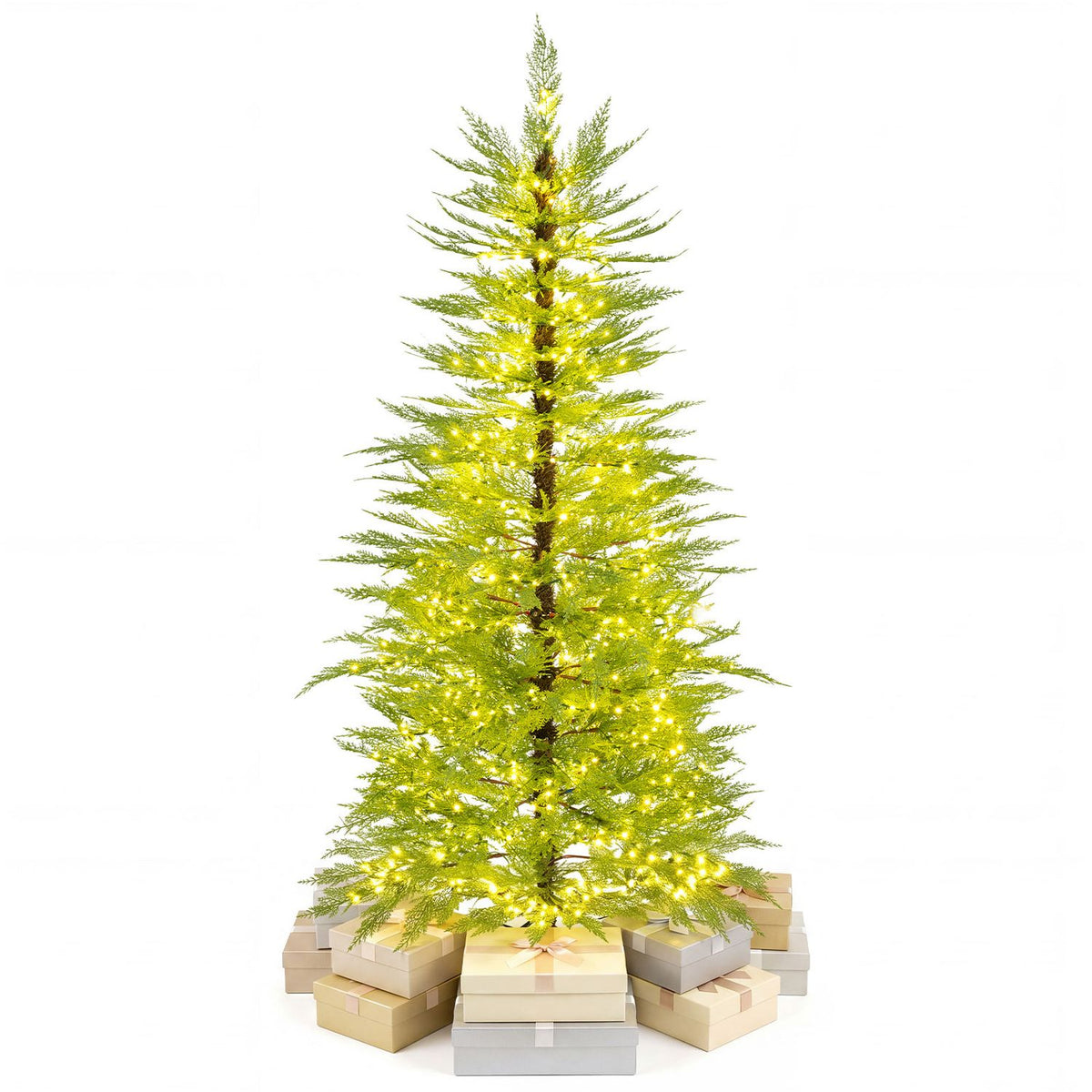 Lit artificial Christmas tree displayed above a cluster of pale wrapped boxes on white.