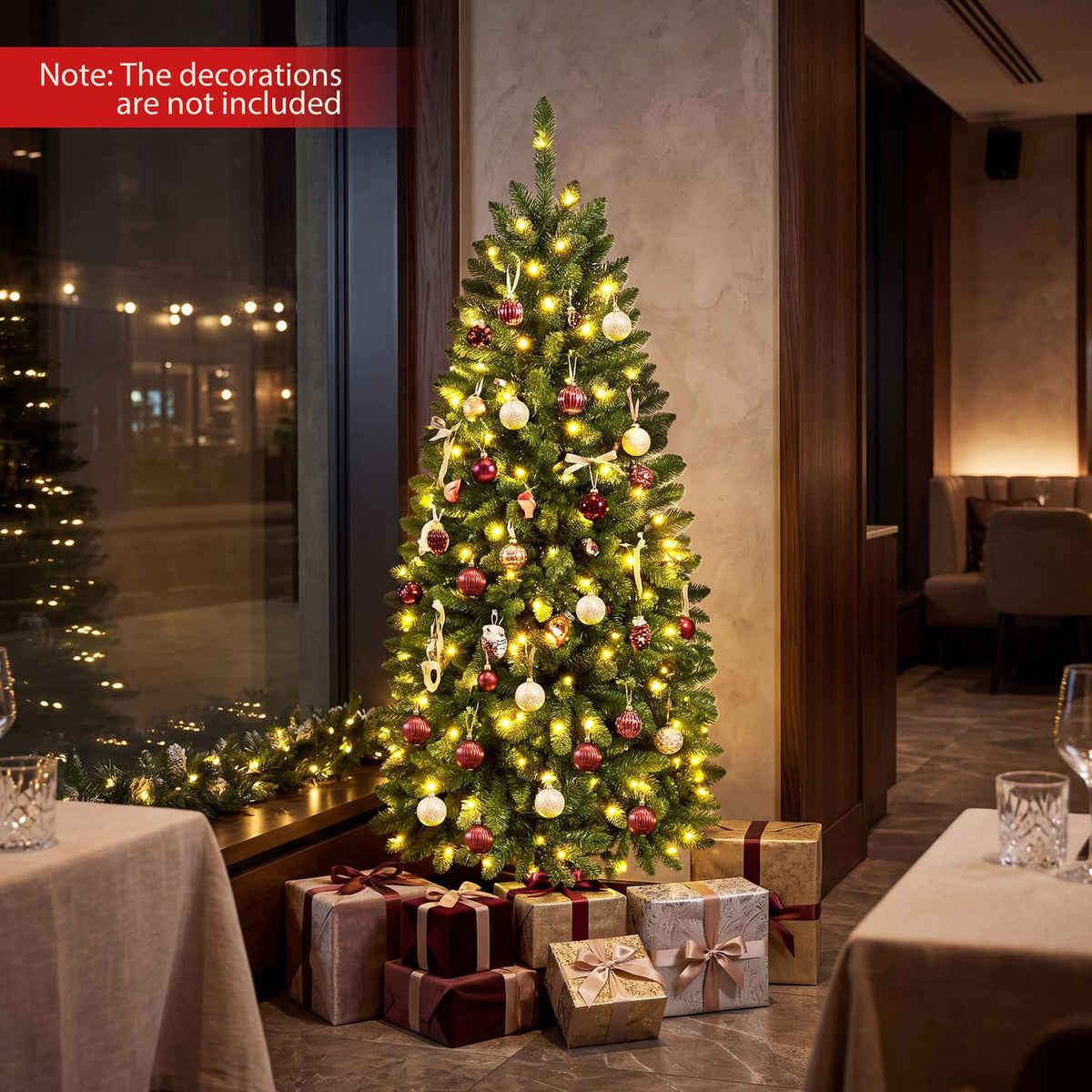 A glowing decorated Christmas tree stands among wrapped presents in a dim dining room.