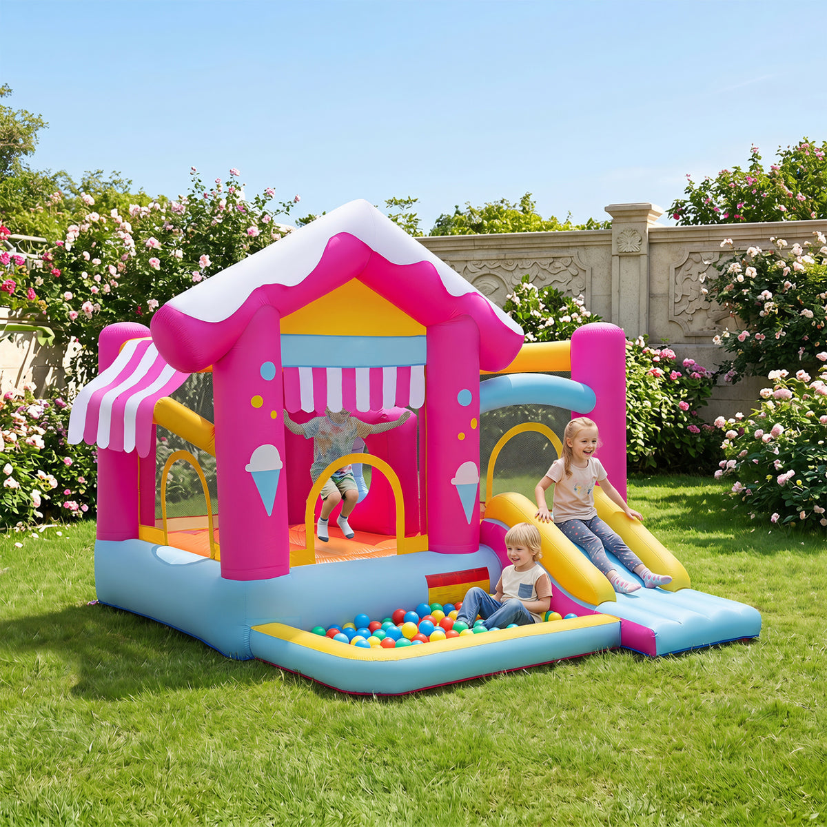 Bright pink-and-blue inflatable play house with a ball pit and slide on a lawn, with children playing.