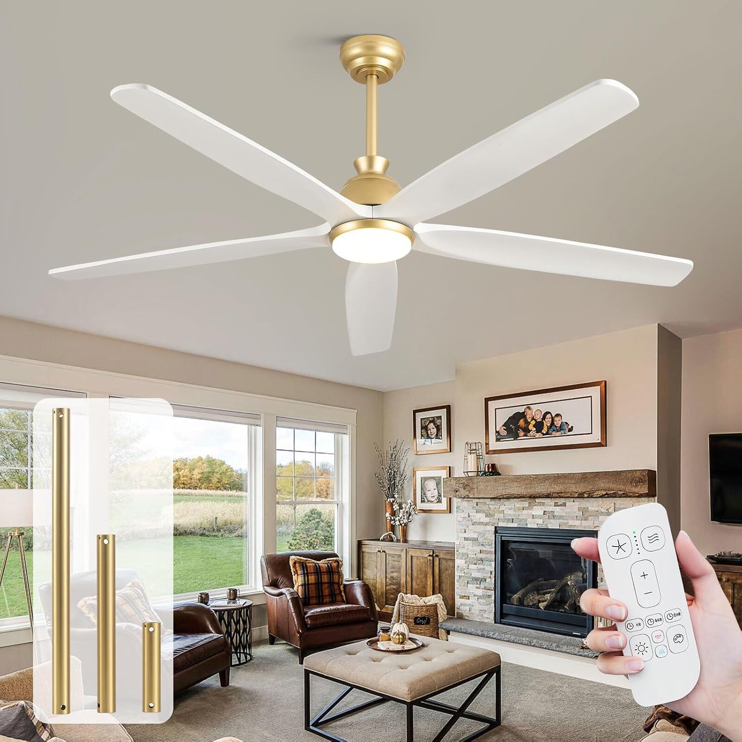 Gold-brass ceiling fan with white blades mounted over a cozy living room with fireplace, tufted ottoman, and large windows