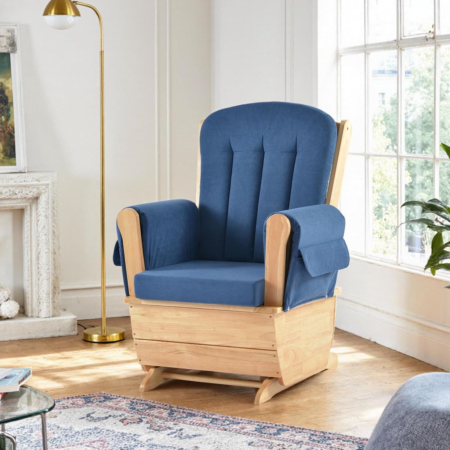 Light wood glider chair upholstered in medium blue fabric placed near a tall floor lamp
