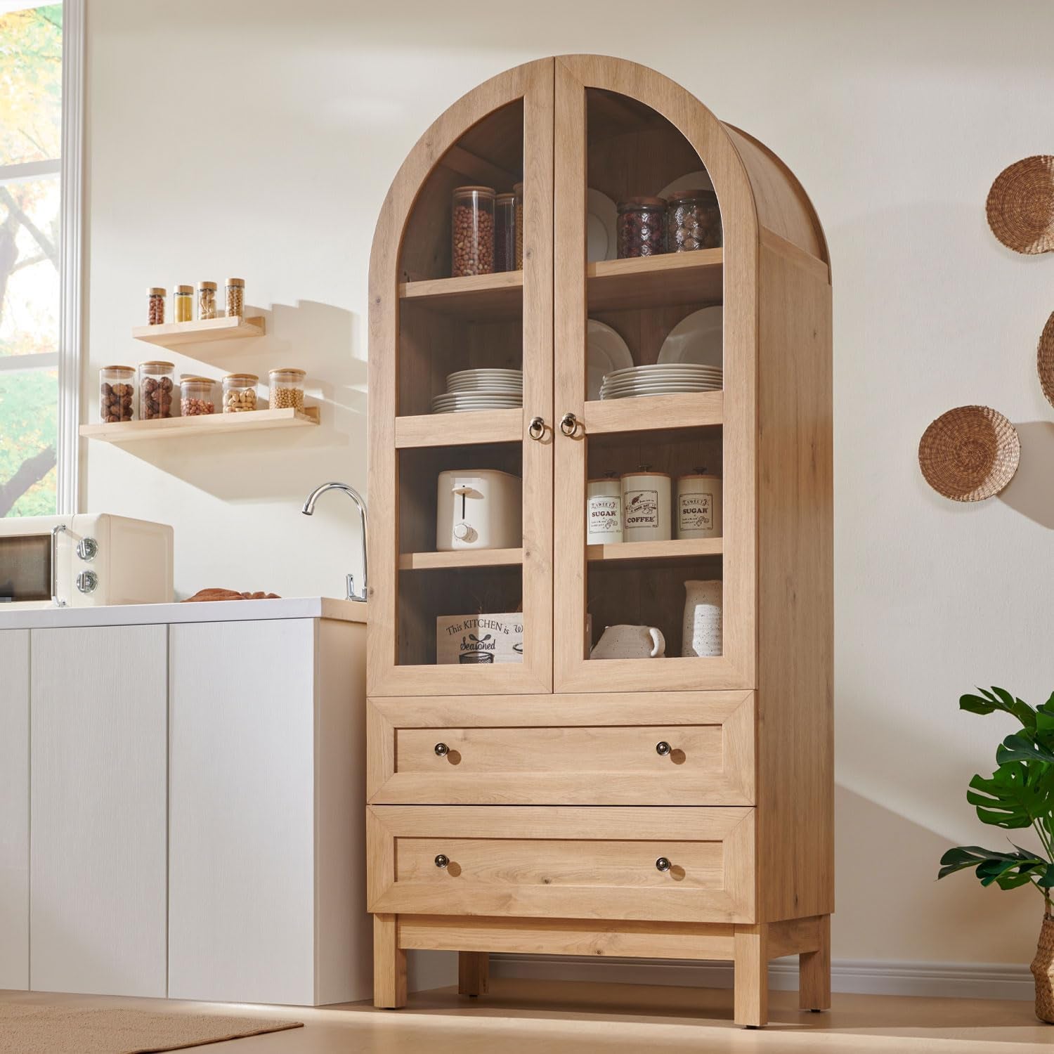 Arched tall pantry cabinet in natural wood finish, front-left view in a bright kitchen setting