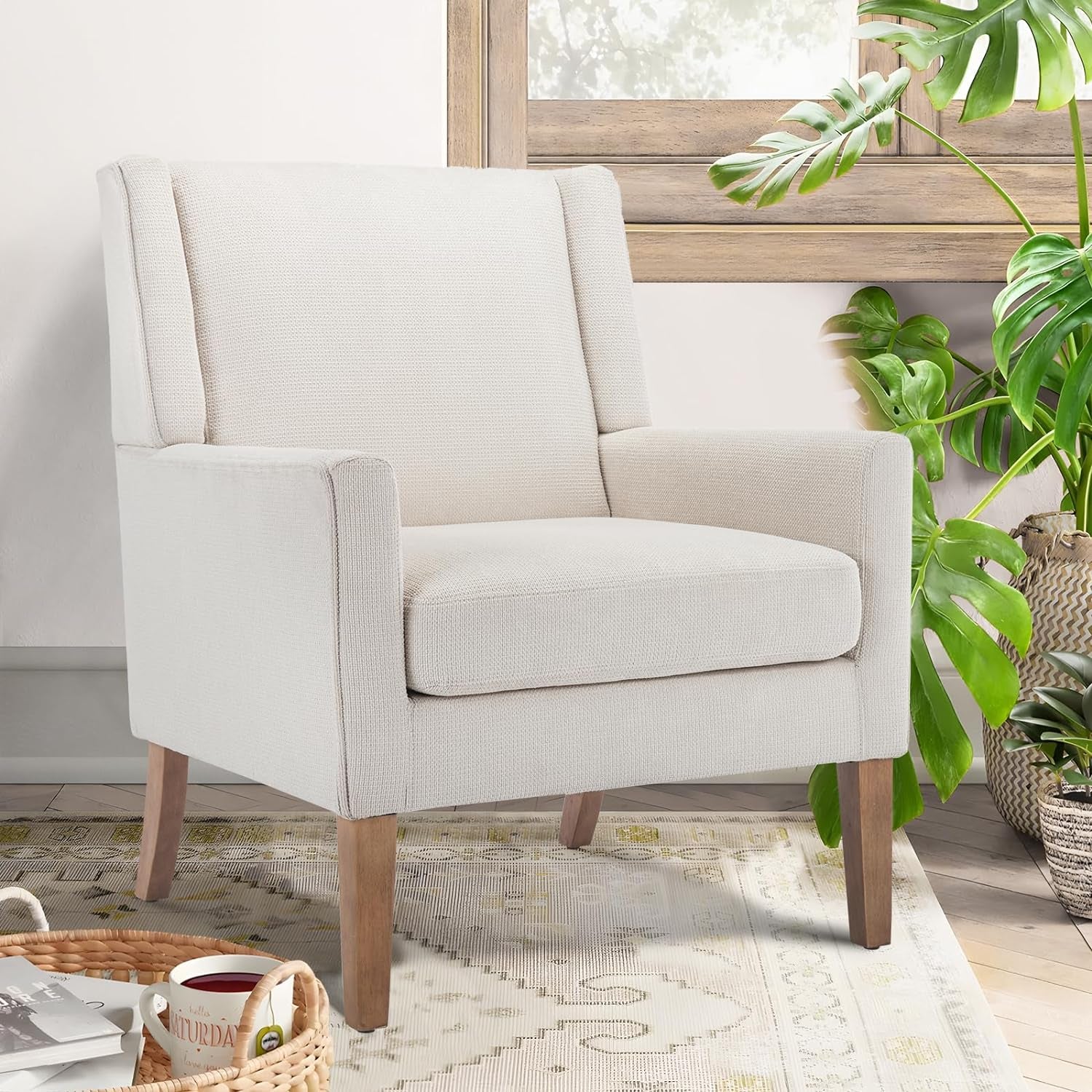 Single cream chenille wingback chair with tapered rubberwood legs next to a window and leafy plant.