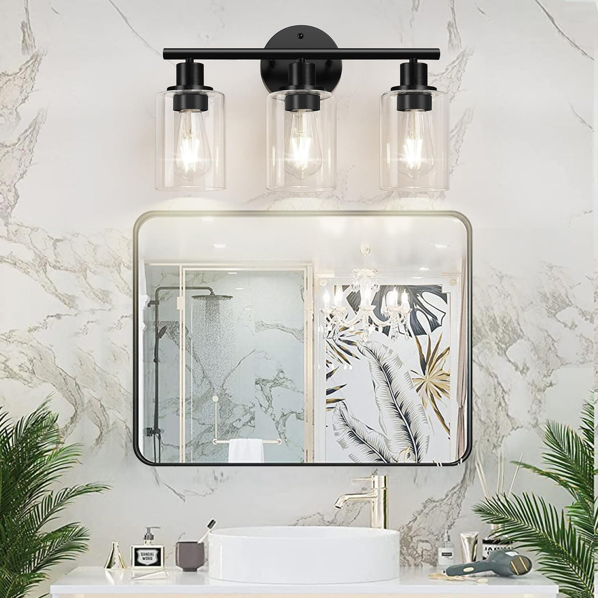 Black three-light vanity fixture with clear glass shades mounted above a framed mirror and sink in a bathroom scene