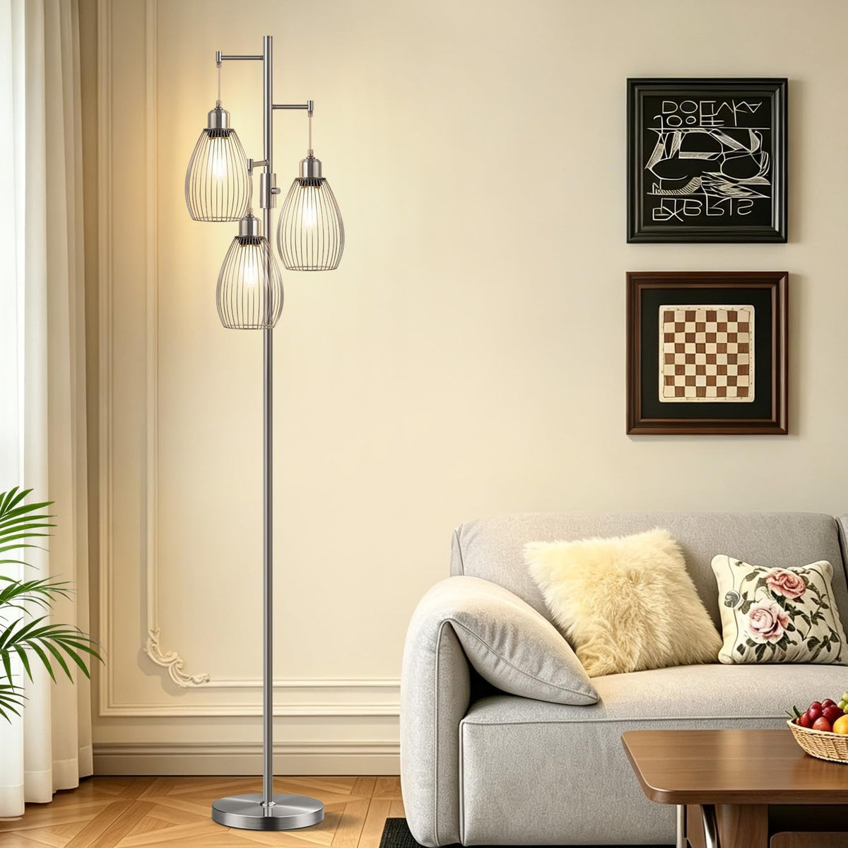 Silver three-light floor lamp with wire cage shades next to a light gray sofa and framed wall art.
