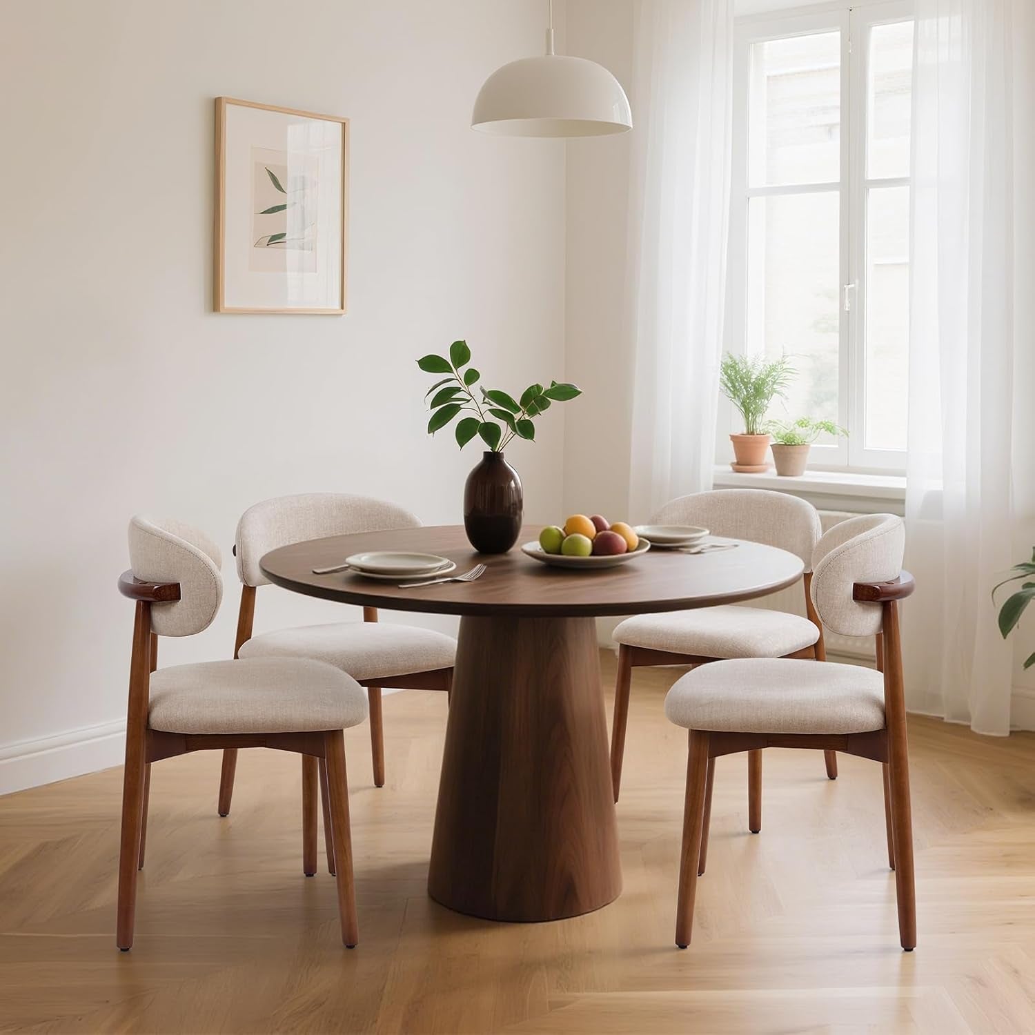 Four beige upholstered dining chairs surround a round wood table in a bright room.