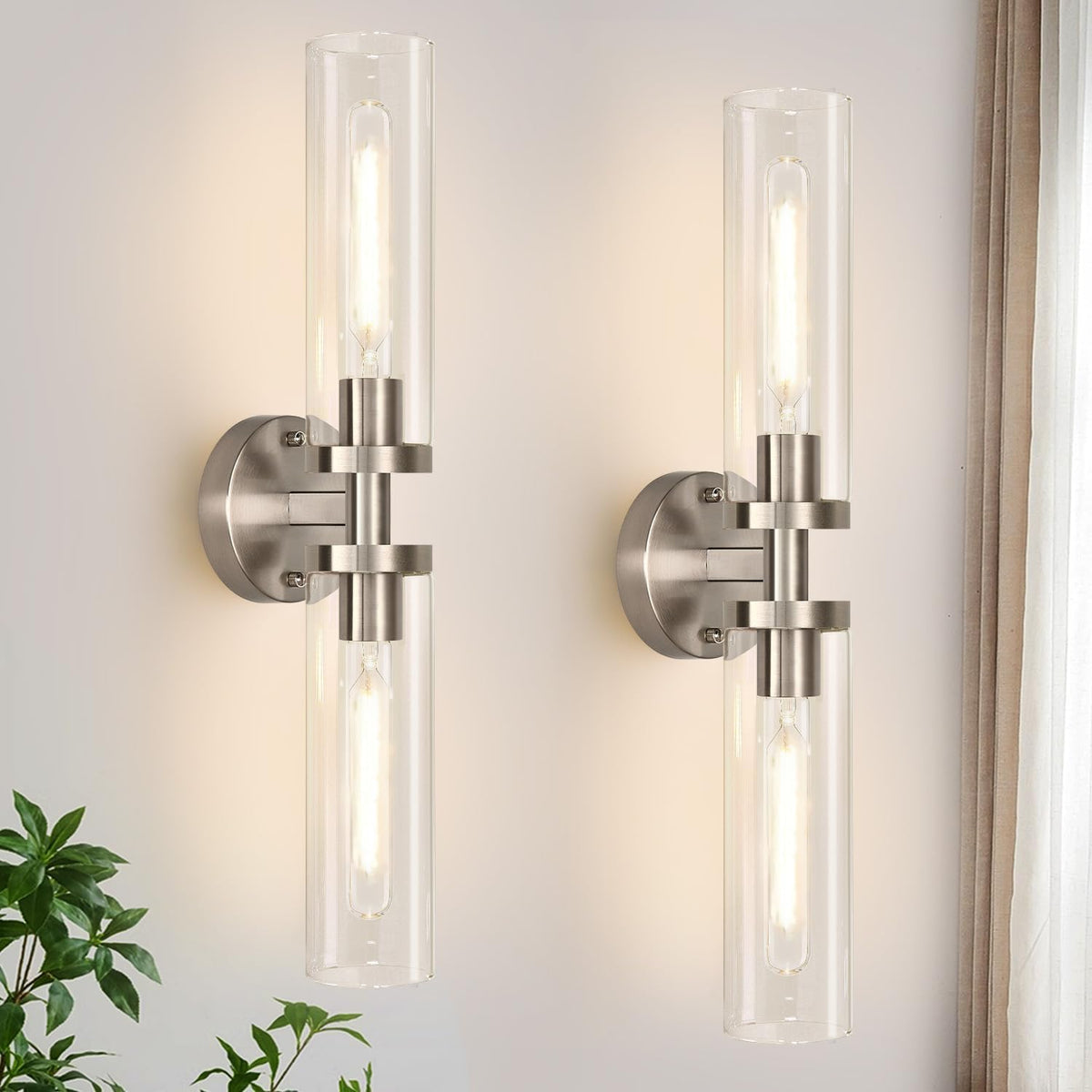 Close-up of two vertical brushed silver metal sconces with clear glass shades