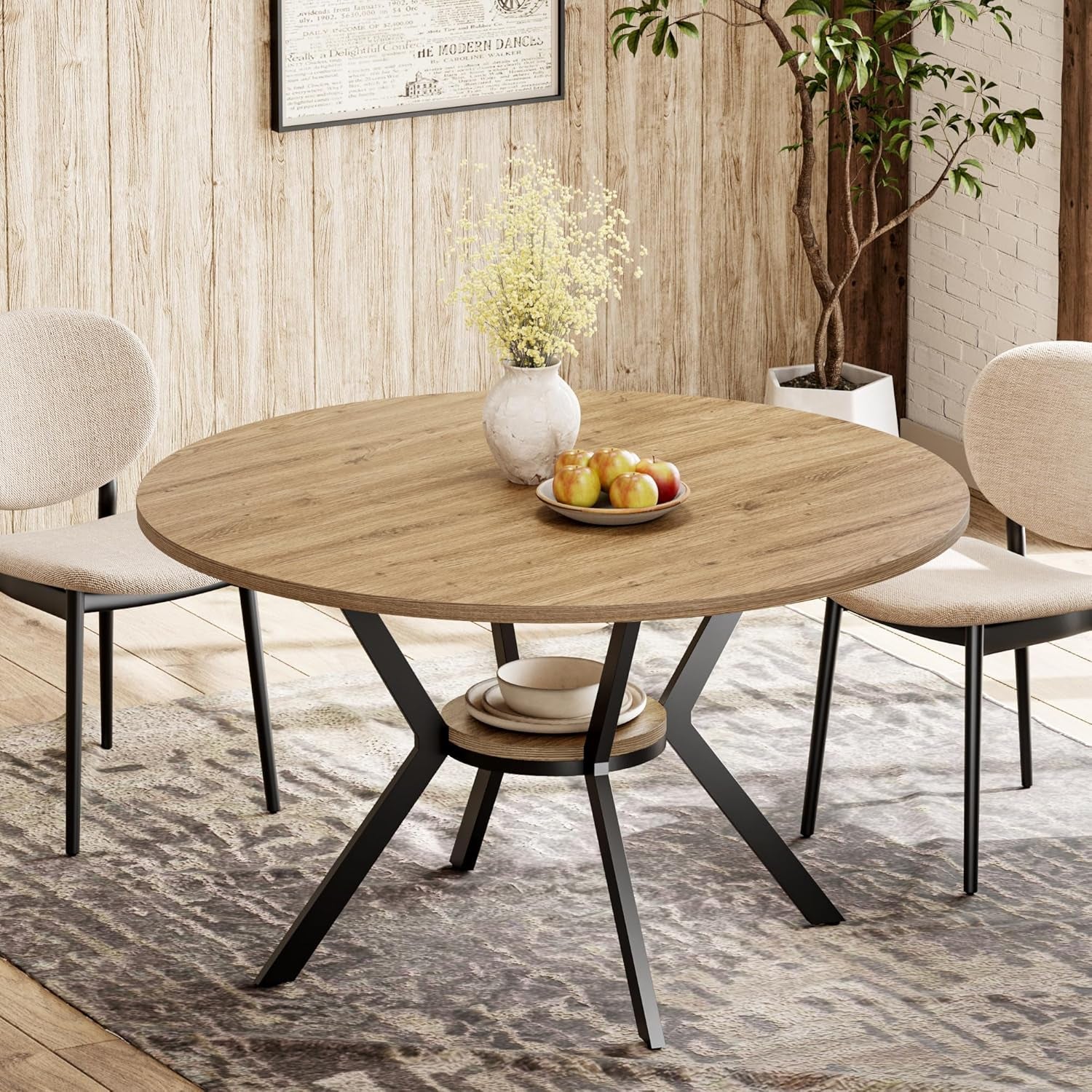 Round wood-look dining table with black metal angled legs and central shelf, set with a vase and bowl of apples
