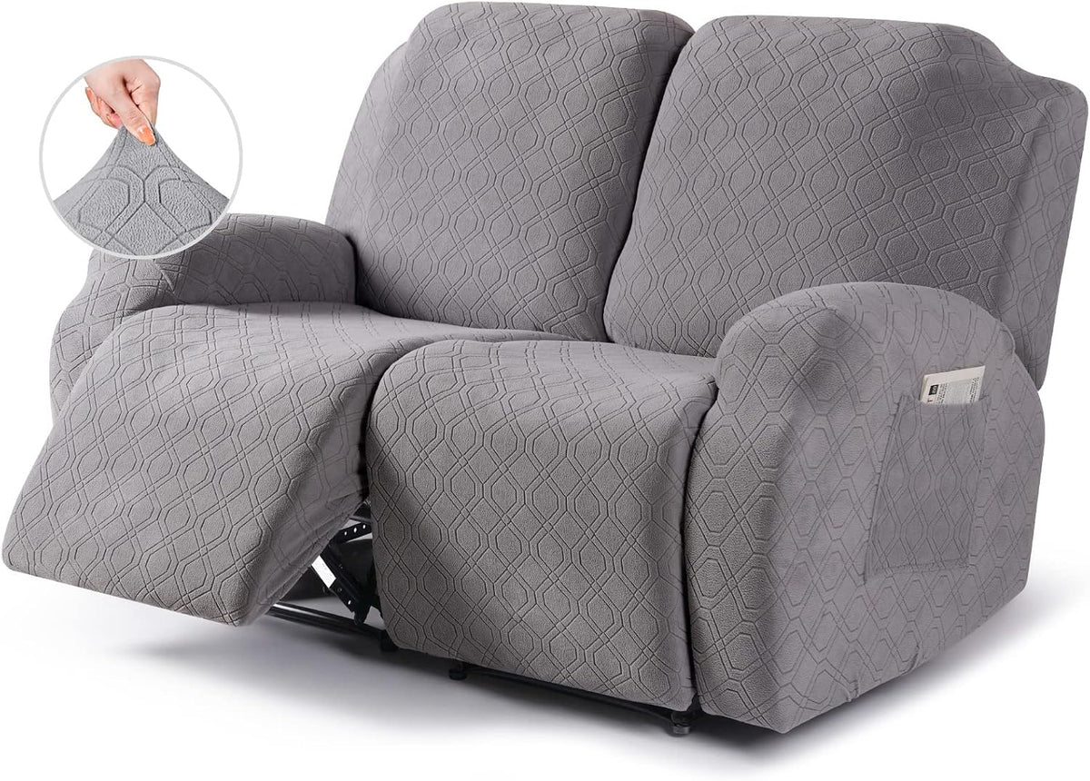 Three-seat light-gray reclining sofa with one footrest extended, textured stretch slipcover and arm pocket holding a