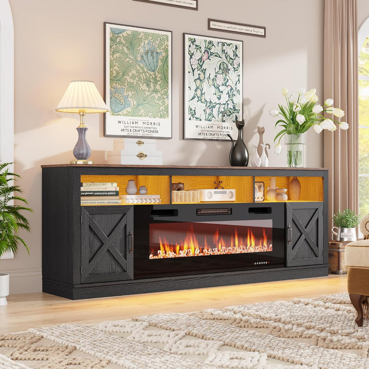 Black farmhouse console with lit electric fire, barn doors and decorative vases on top in a bright living room corner